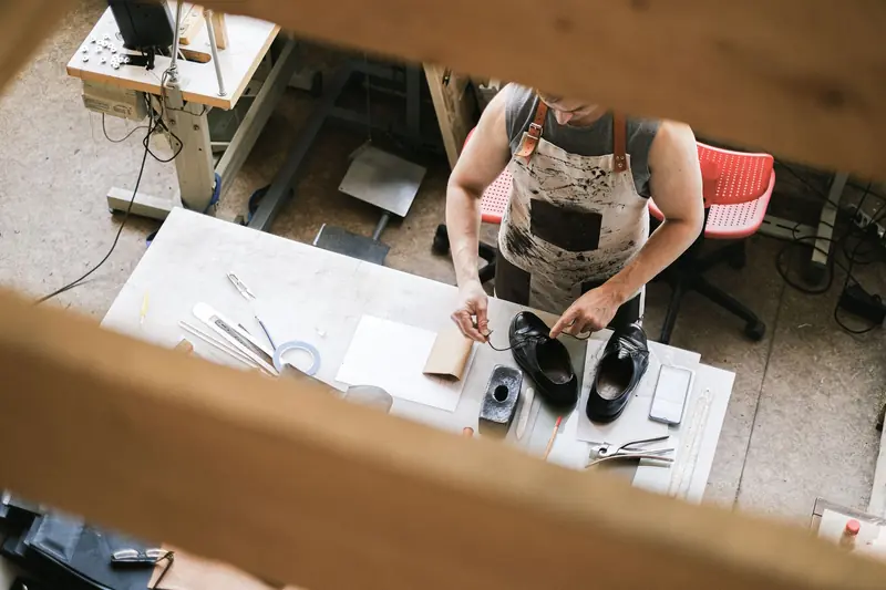 Top view of a leather artisan at work in a workshop, focusing on shoe crafting