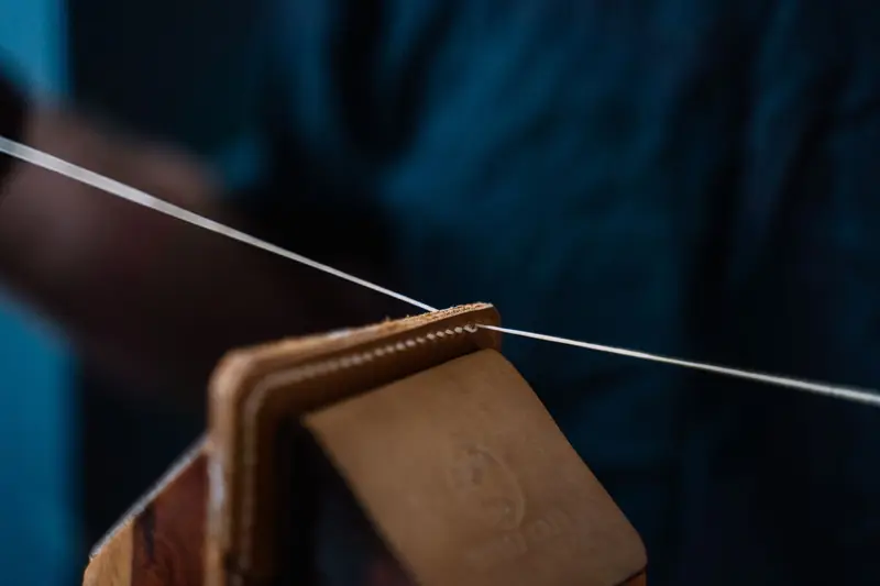 Close-up of handmade leather wallet being stitched, showcasing craftsmanship and precision
