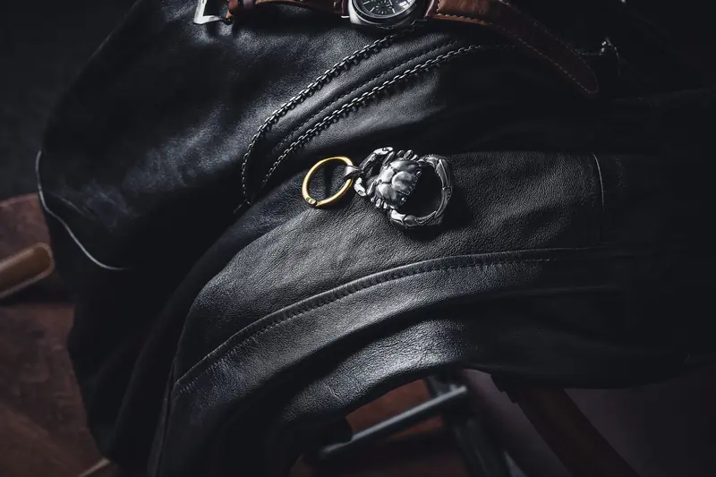 Stylish leather draped with a silver keychain and wristwatch in a moody setting