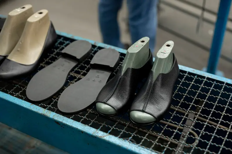 Detailed view of shoe making process with leather uppers and molds on work table