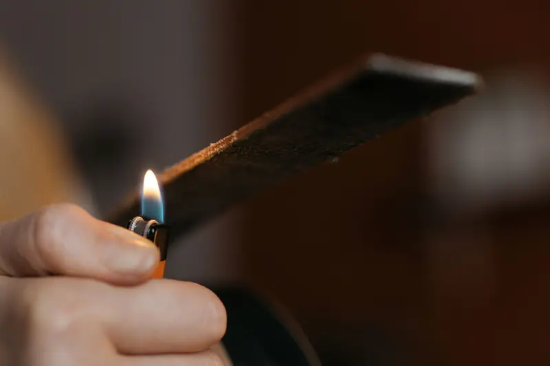 Artisan carefully burns leather edge for crafting precision and finish