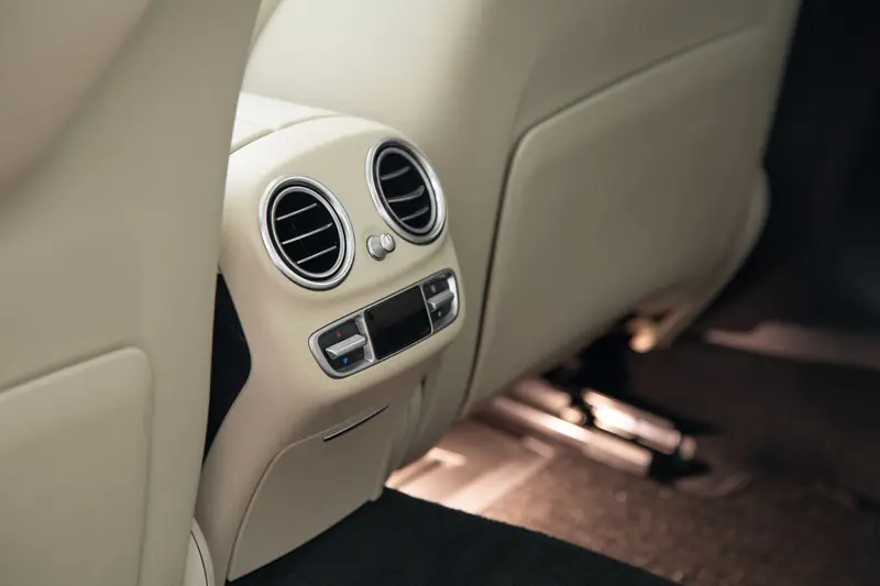 Close-up view of a luxury car's rear air conditioning vents and beige leather interior