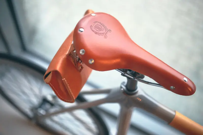 Detailed close-up of a vintage leather bicycle saddle and handlebar indoors